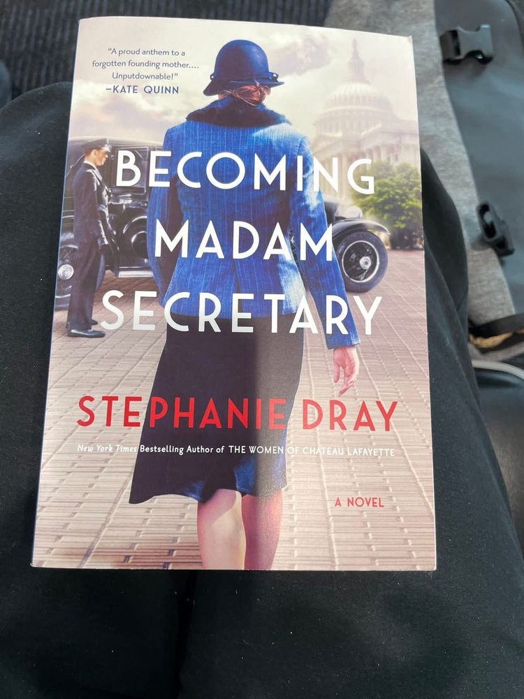 Book cover. A woman walks away from the viewer, wearing a black skirt, blue jacket, and a smart blue hat.  The cover reads "A proud anthem to a forgotten founding mother.
Unputdownable!"
-KATE QUINN
BECOMING
MADAM
SECRETARY
STEPHANIE DRAY
New York Times Bestselling Author of THE WOMEN OF CHATEAU LAFAYETTE
A NOVEL