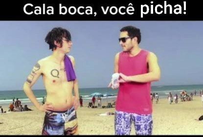 Dois homens brancos em uma praia, enquanto um deles passa protetor solar o outro diz "cala a boca você picha!".