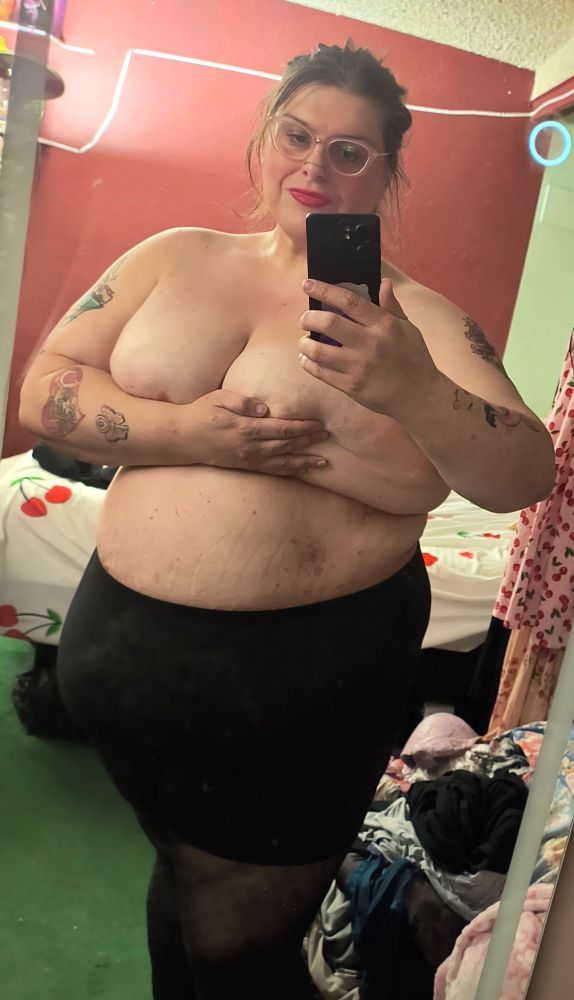 Cherry holding her boobs so she doesn't fall over. She is wearing black tights and a smile.