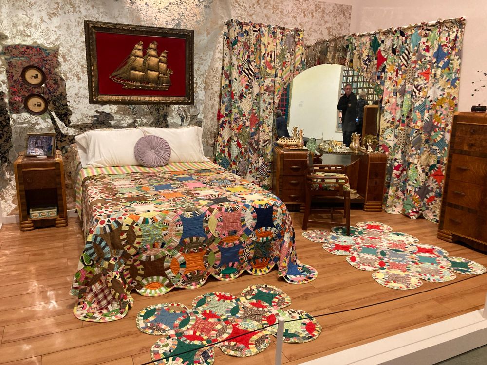 Kaleidoscopic overwhelming room installation. Silver metallic wall paper. Double ring quilt on bed, mats on floor, curtains around vanity. Movement and color everywhere. More is more joy. 