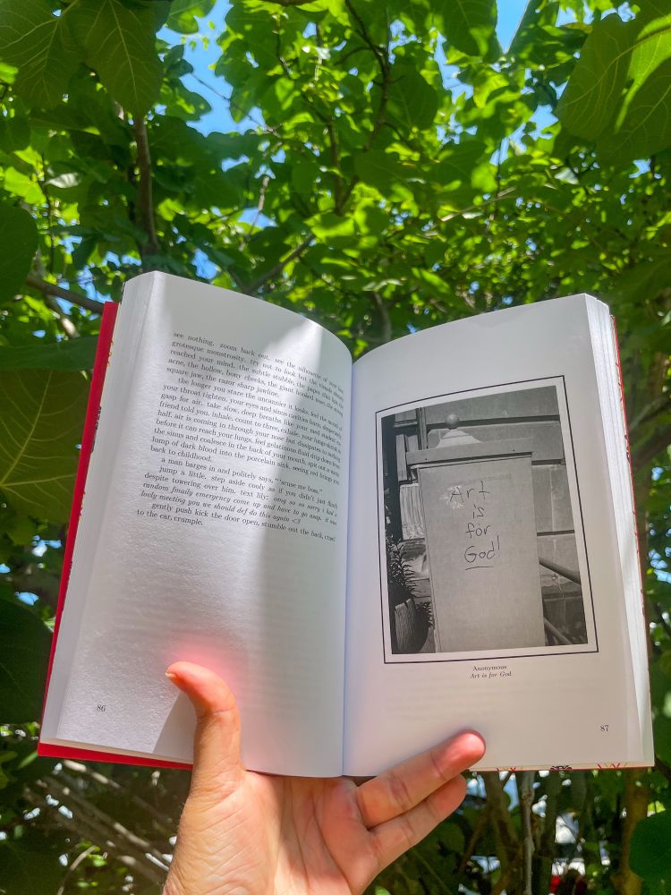 A book open to text and a black and white image of graffiti that reads “art is for god!”