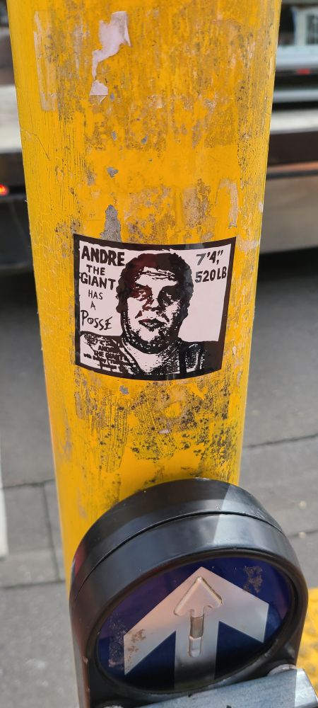 A sticker on a yellow street post, probably a crosswalk sign in Wellington, Nz. 

The sticker has a bust relief drawing of André the Giant in the center. To the left the text says "Andre the giant has a posse" On the right it says "7'4" 520LB"