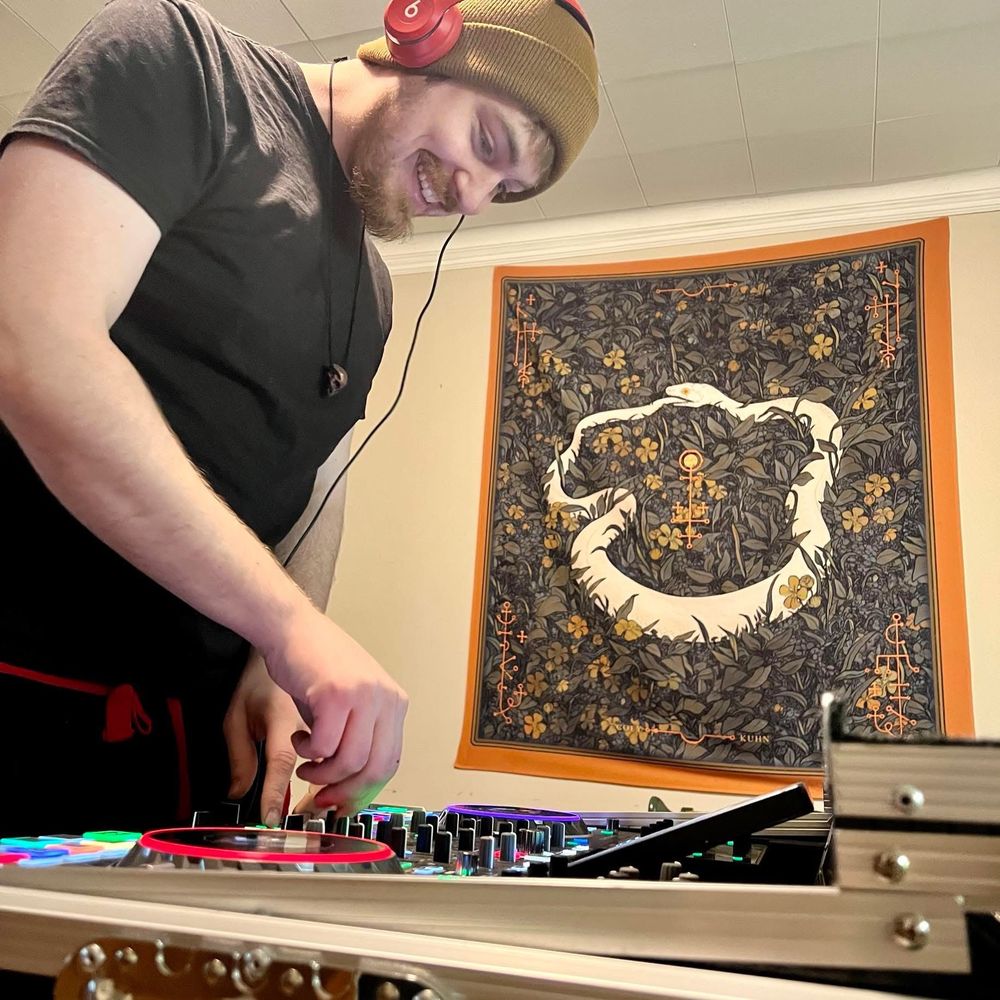 Man standing on left side of photo using a dj controller 