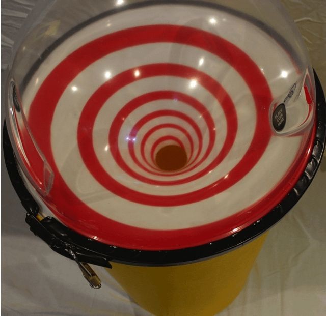 A photo taken from above of a red and white spiral shaped charity coin collector. 