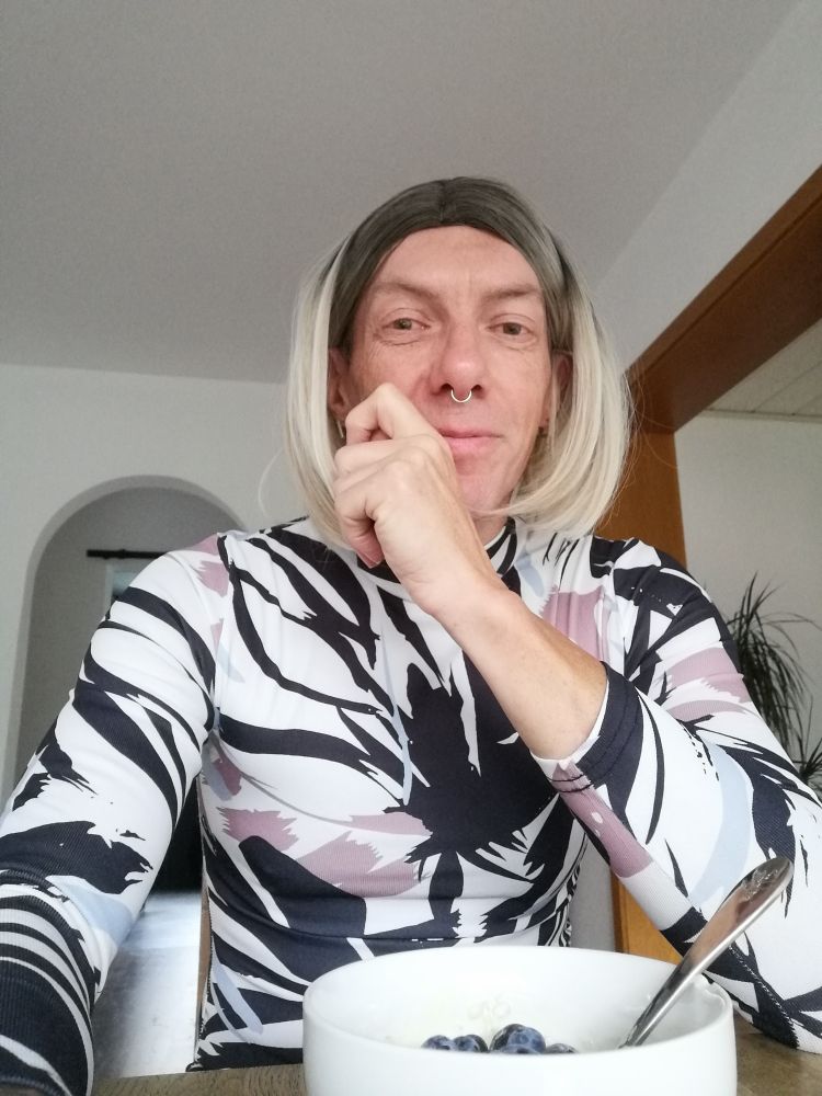 Eine Person sitzt am Frühstückstisch mit einer Schale Müsli