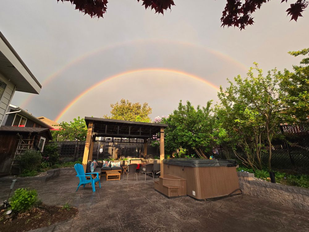 Photo of a double rainbow over a backyard patio