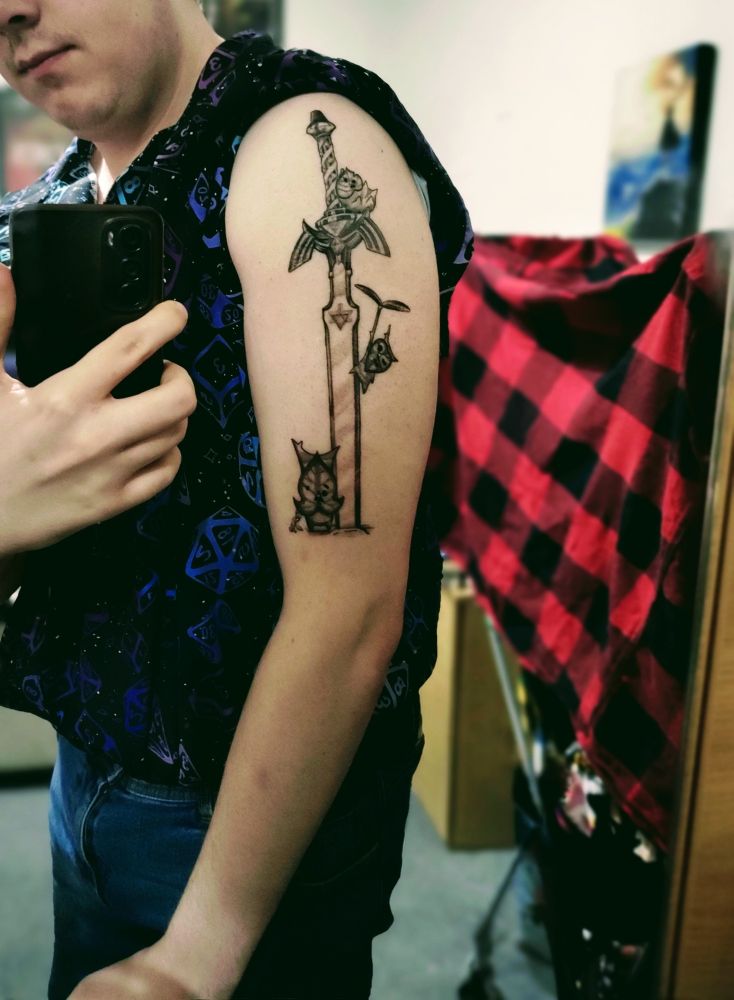Me showing off my zelda tattoo. It is the master sword, planted into the ground, with three Koroks surronding it. One kn the ground, one flying using a propeller leaf and one sitting on the handle. It is imprinted on my right arm. Please ignore my clothes they are drying I promise