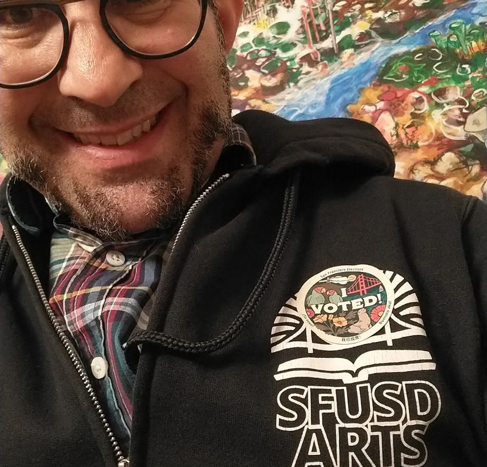 Man looking at camera. You can see a San Francisco "I voted" sticker on his SFUSD ARTS hoody.