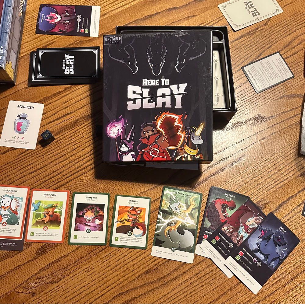 Here to Slay game box top and cards from the game 