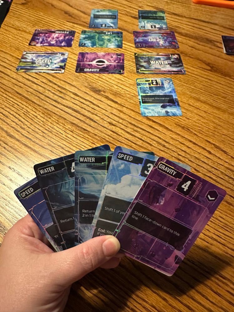 A hand holding 5 cards that read water, speed or gravity at the top. 