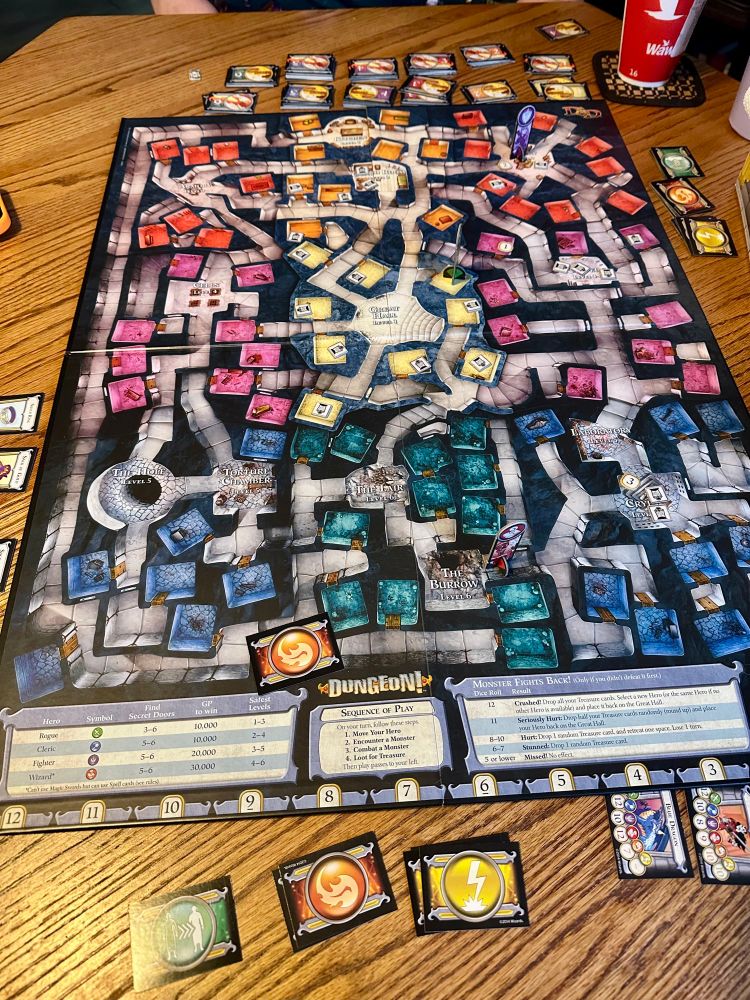Board game showing multiple paths and different sized chambers with some game cards surrounding the sides 