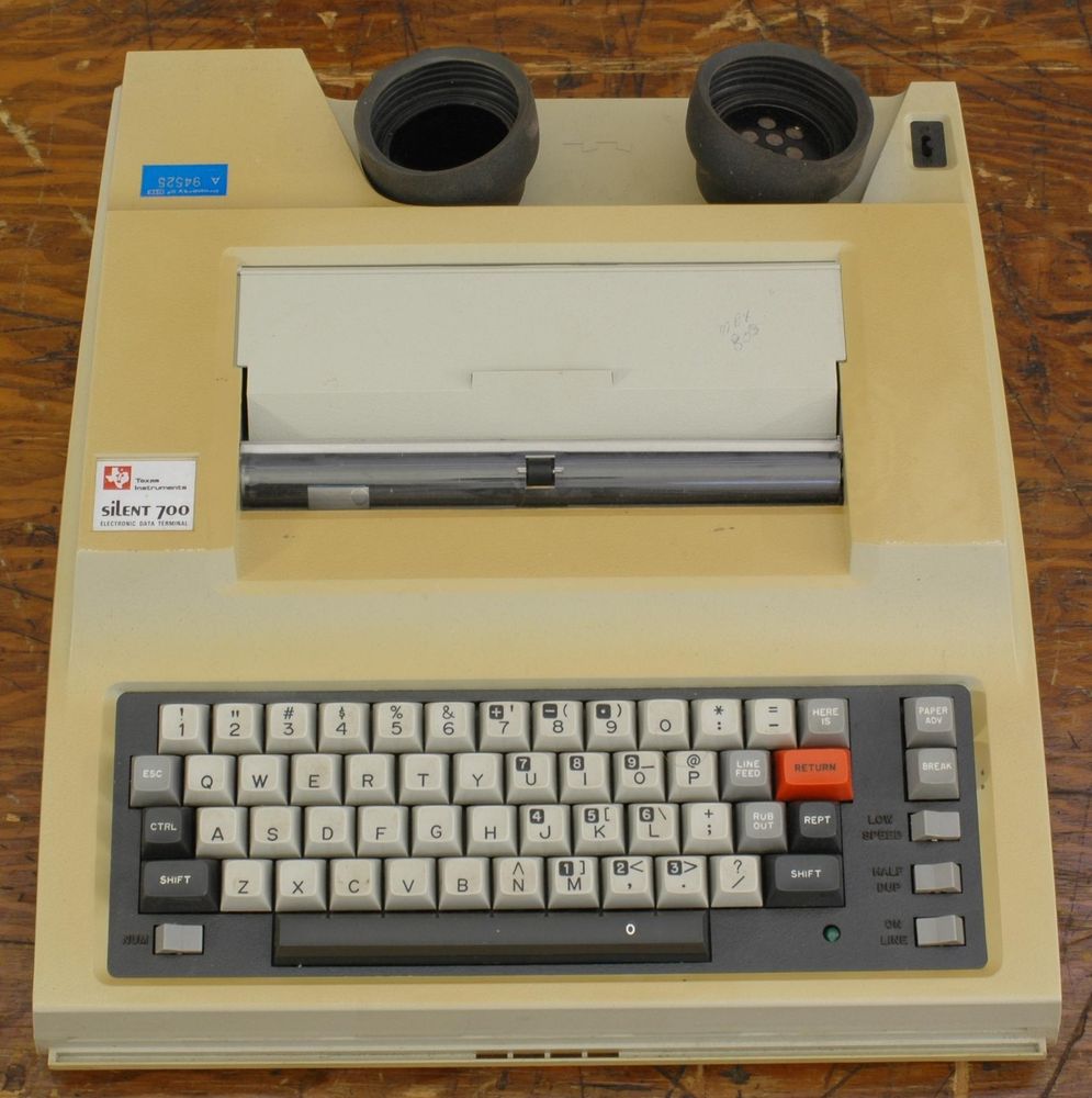 An image of a Texas Instruments Silent 700, its plastic housing yellowed with age. This machine has a pair of rubber cups to hold an old-fashioned corded phone's receiver, a thermal printer, and a simple keyboard.