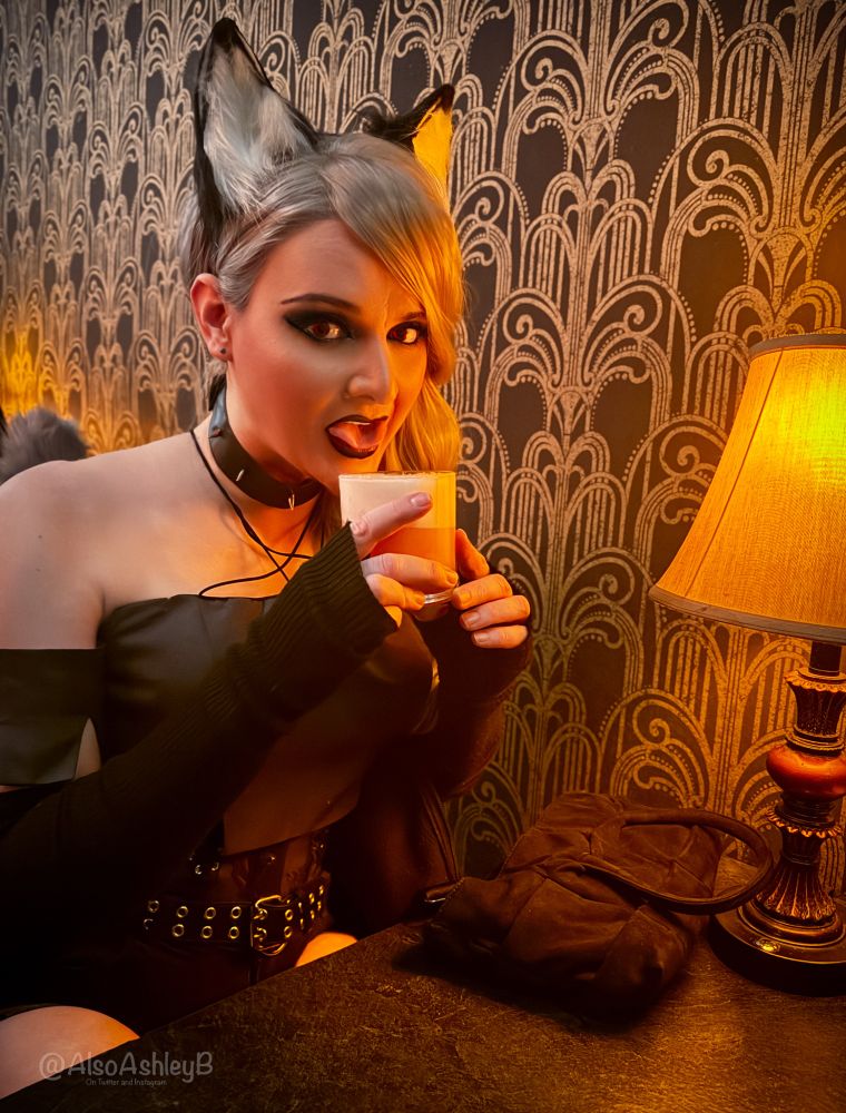 Ashley lapping up her drink while dressed as Loona at a bar, cool warm lights