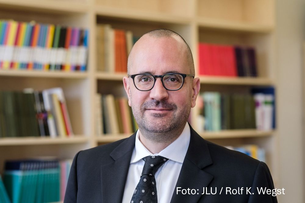 Porträtfoto von Prof. Dr. Dirk Uffelmann vor einem Bücherregal