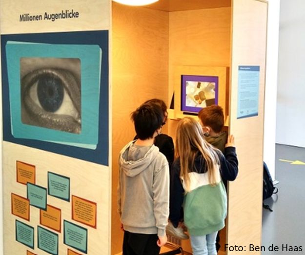Eine Gruppe von Kindern steht im Gießener Mathematikum in dem Exponat der JLU-Forschenden zur Messung von Blickbewegungen.