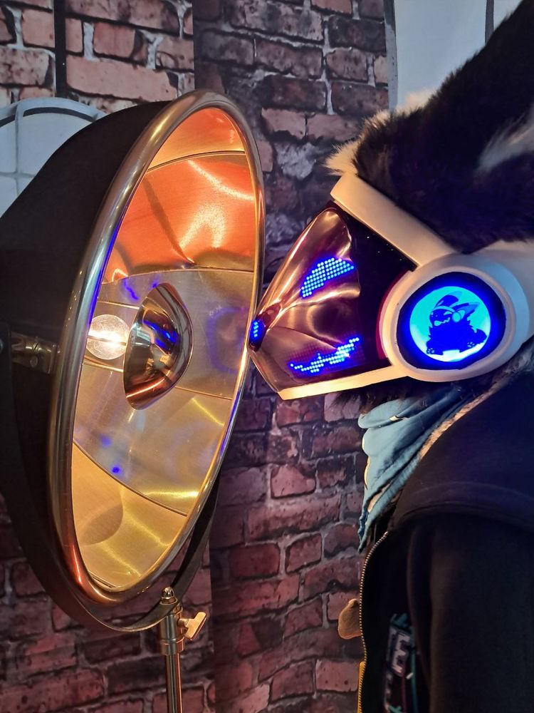 A protogen fursuiter staring into a giant lamp