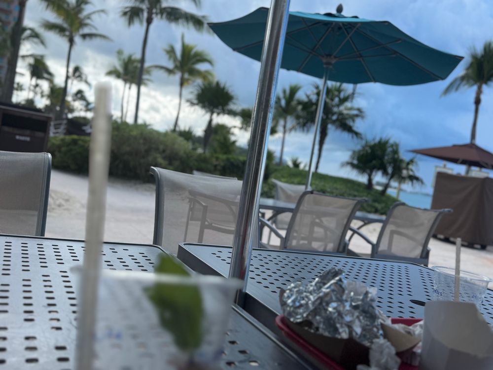 A photo of a table holding an empty drink against a dark, cloudy Caribbean sky. 