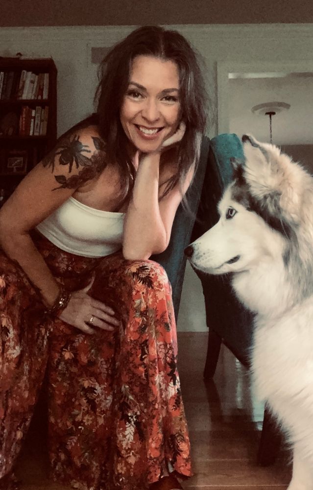 A picture of me in orange loose pants with my Siberian Husky on profile.