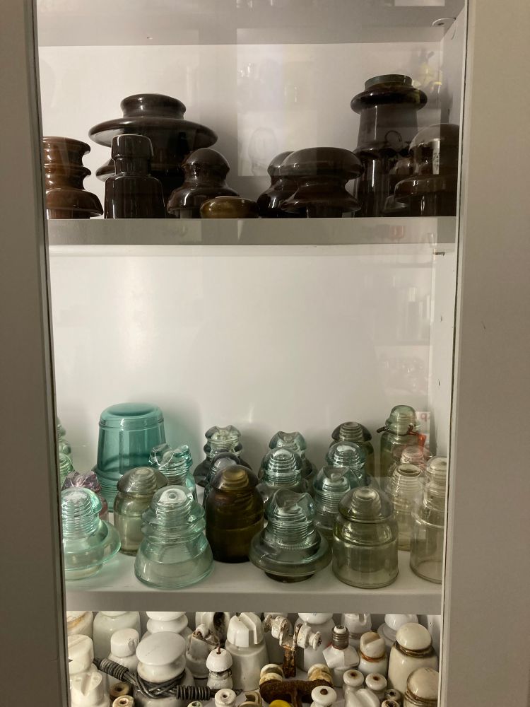Glass insulators in a white cabinet with glass doors 