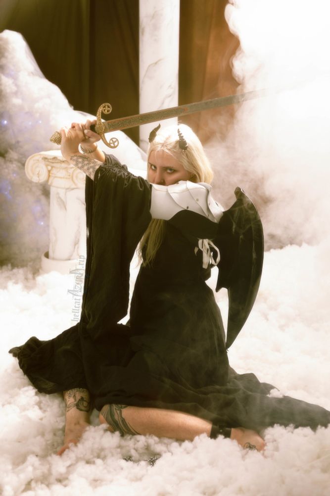 Azura sitting amongst heavenly white clouds and marble columns, wearing a long black dress with draped sleeves, white leather pauldrons, and large black bat wings. They're holding a medieval sword above their head, the tip of the blade disappearing into white clouds of smoke, their leather clad bicep blocking their cheek like the painting Fallen Angel by Alexandre Cabanel, and short black horns protruding out of their glowing golden hair. Their legs are folded, a black leather cuff around their ankle.