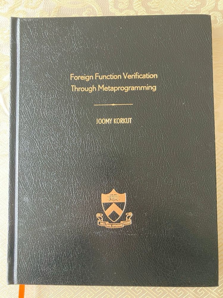 A printed and bound copy of my dissertation. My title “Foreign Function Verification Through Metaprogramming”, my name “Joomy Korkut”, and the Princeton logo are gold foil stamped on a black leather cover.