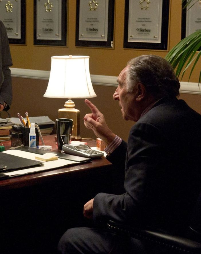 Judd Hirsch sitting at a desk in one of his few scenes in the movie where he fires the main character.