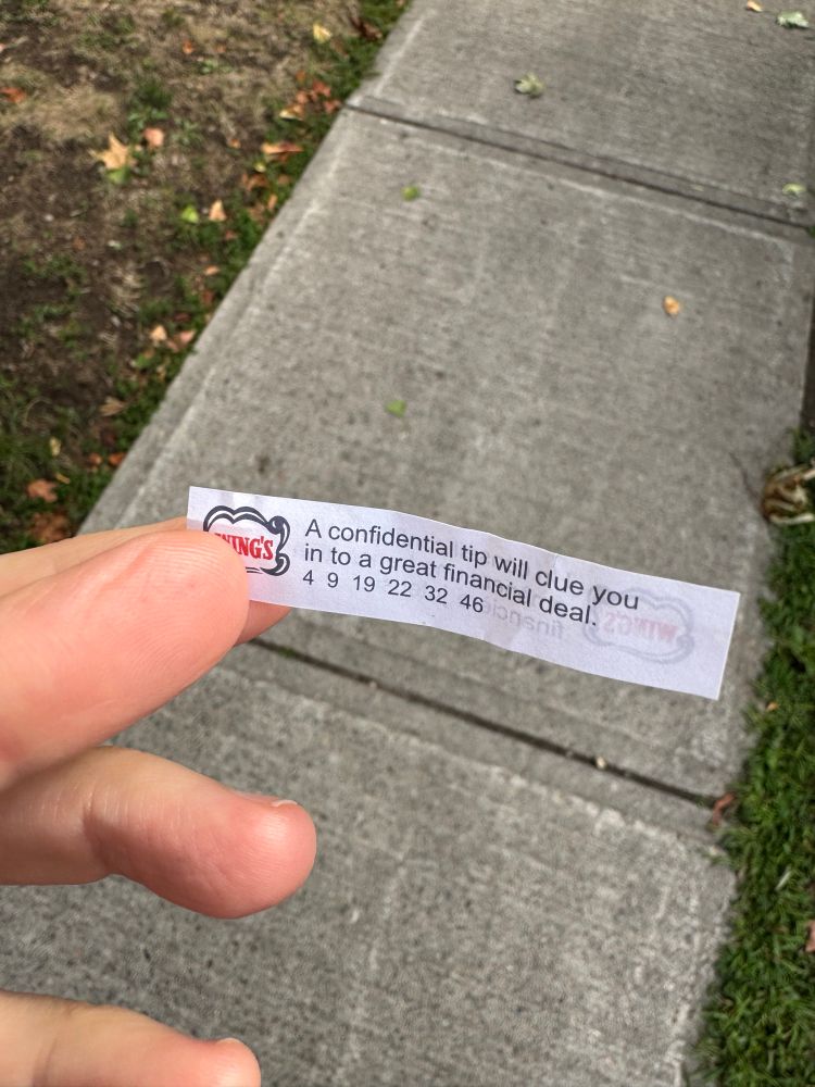 A photo of someone (me!) holding a fortune cookie fortune between her thumb and forefinger). It reads: “A confidential tip will clue you in to a great financial deal. 49 1922 3246“