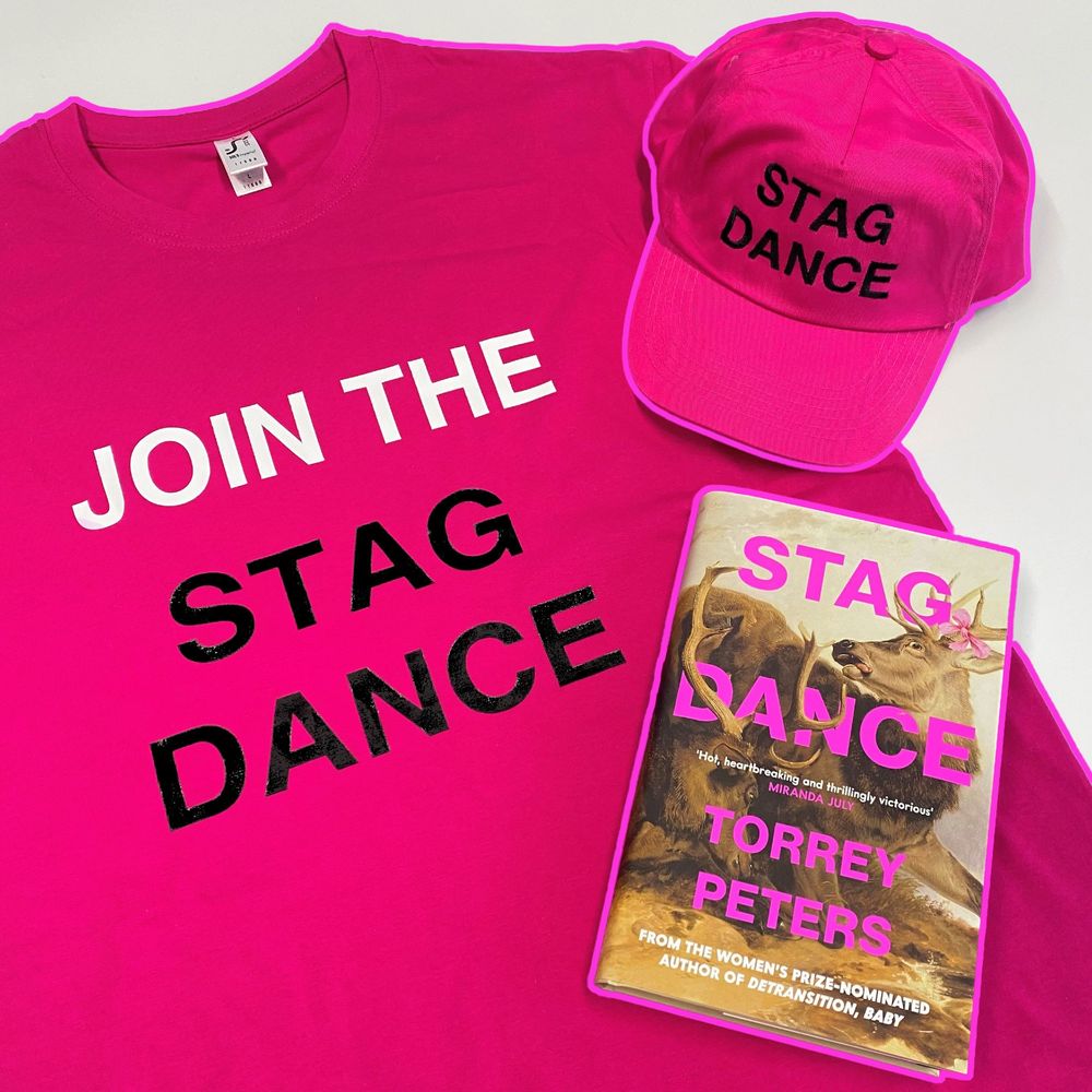 A photo of a pink t-shirt that reads, 'JOIN THE STAG DANCE', a Stag Dance cap and a copy of the hardback book Stag Dance by Torrey Peters. 