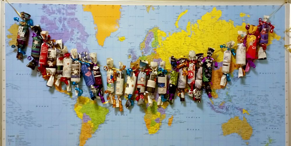Advent calendar, made of toilet rolls wrapped in magazine pages, in front of map of the world