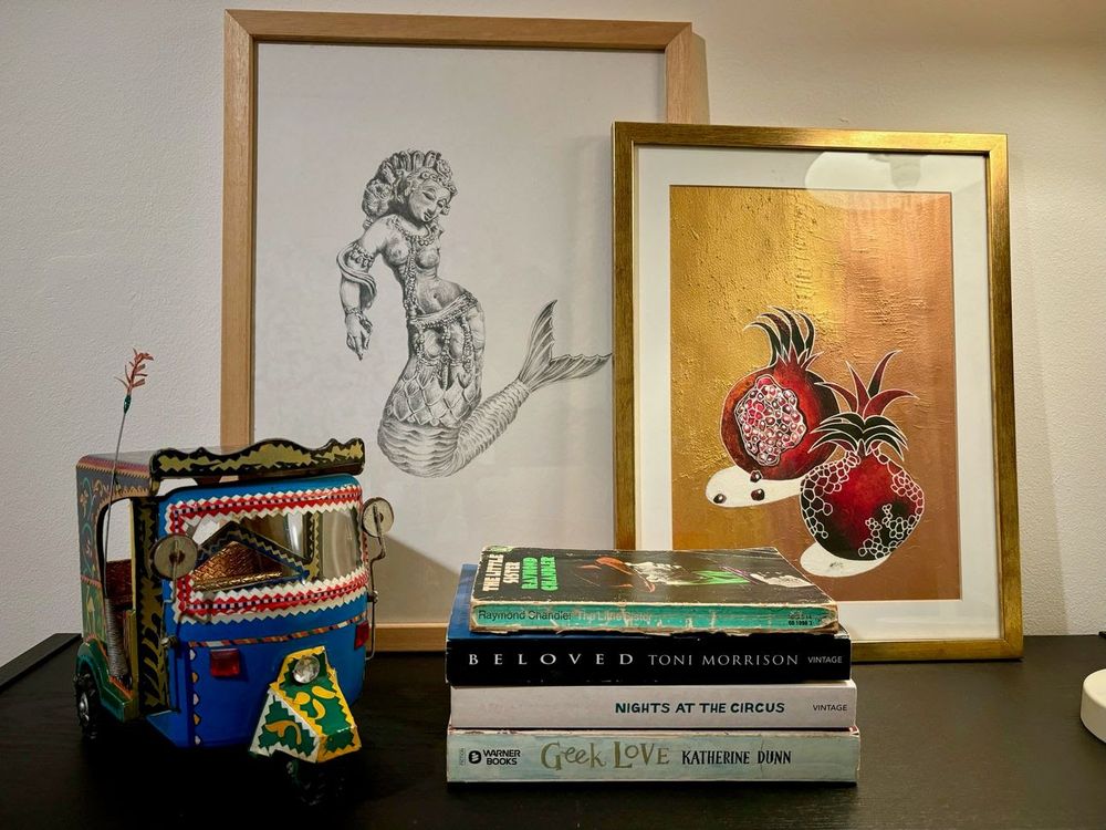 A minimalist bookshelf with two paintings and four books
