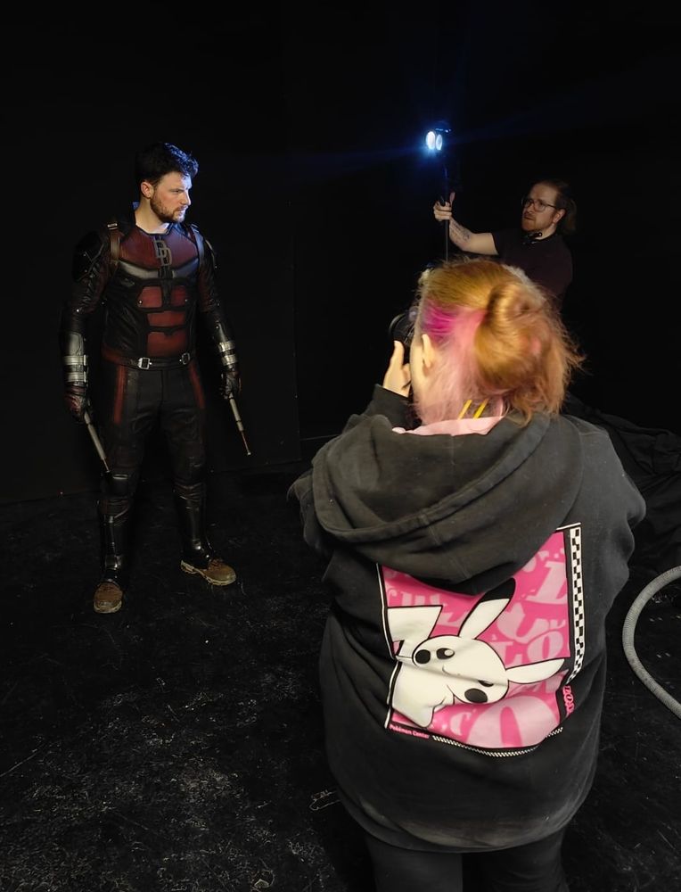 Ben posing as Daredevil. He has the helmet off and is in the blackout room. Amber (picsbyambae) is taking the photo and Nicholas (visionvssight) is holding the lights.