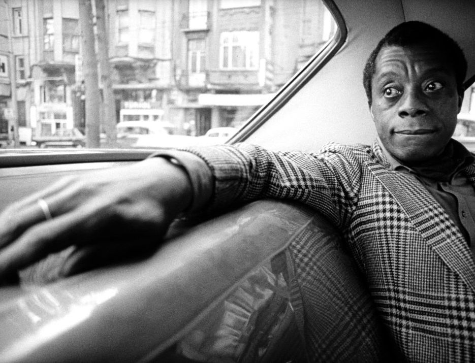James Baldwin in the back seat of a car.