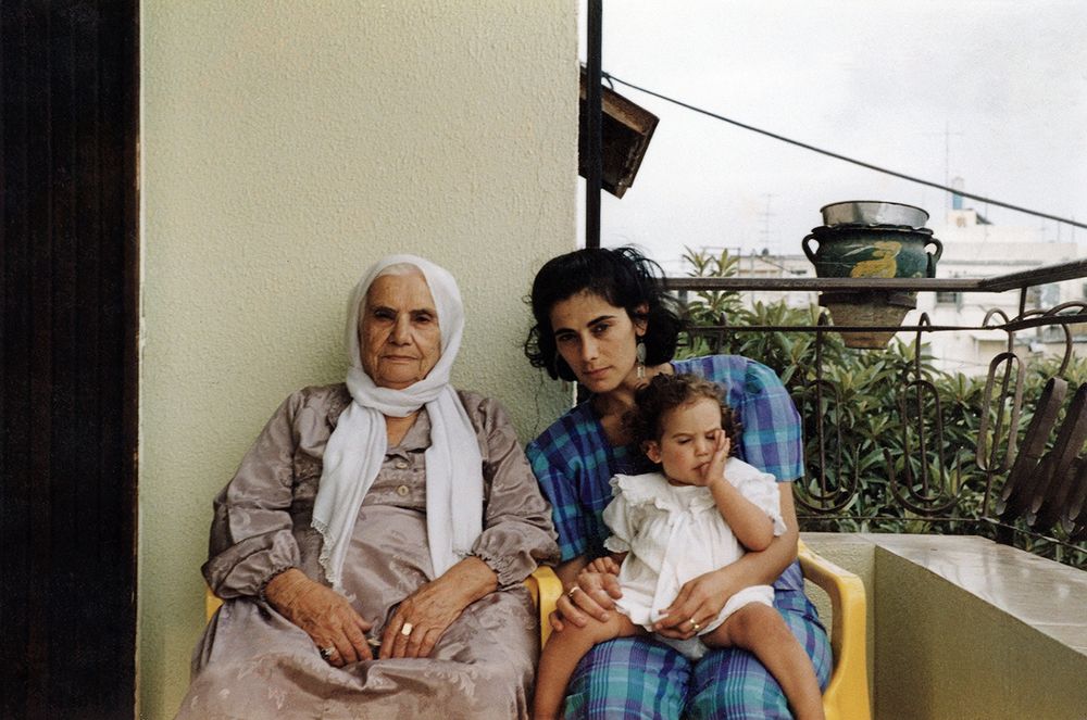 Two women and a baby sitting on a balcony.