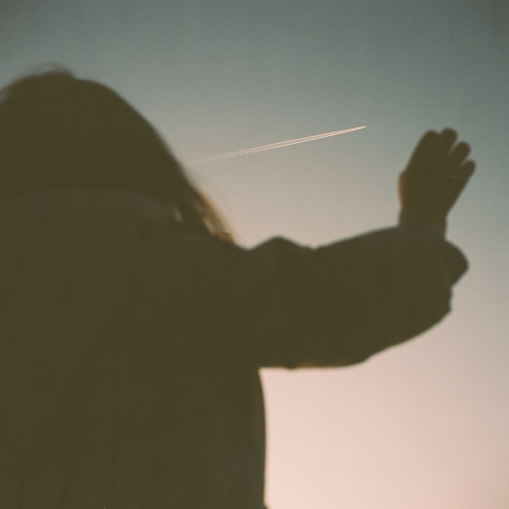 child looking up and pointing at the sky as a plane flies by. 