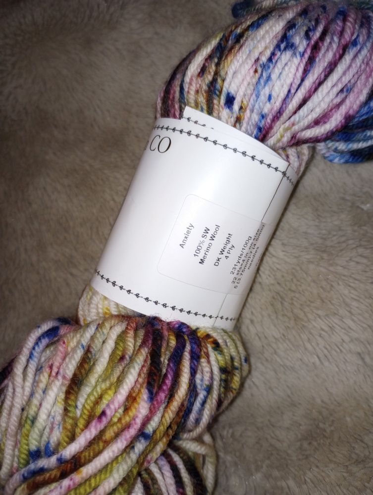 Hand dyed yarn in the color way of "anxiety" a cream with sporadic pops of jewel tones