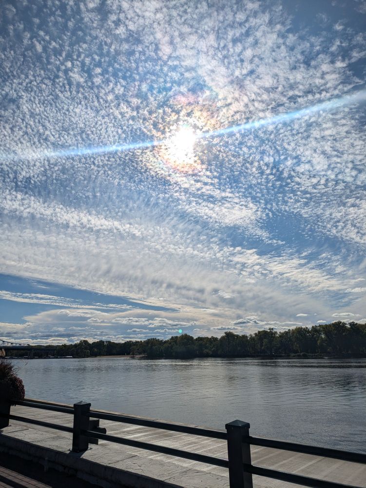 A blue sky mottled with numerous small clouds. The sun beaming behind them, giving off slight hints of pink and yellow.

Reminds me of Starry Night.