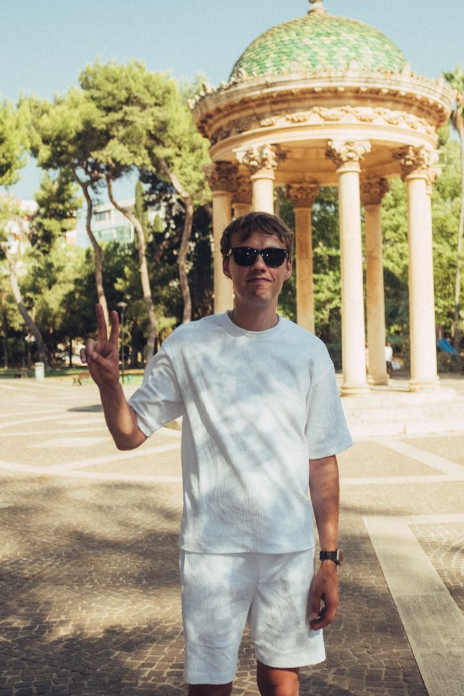 Markus standing in a park showing the peace sign