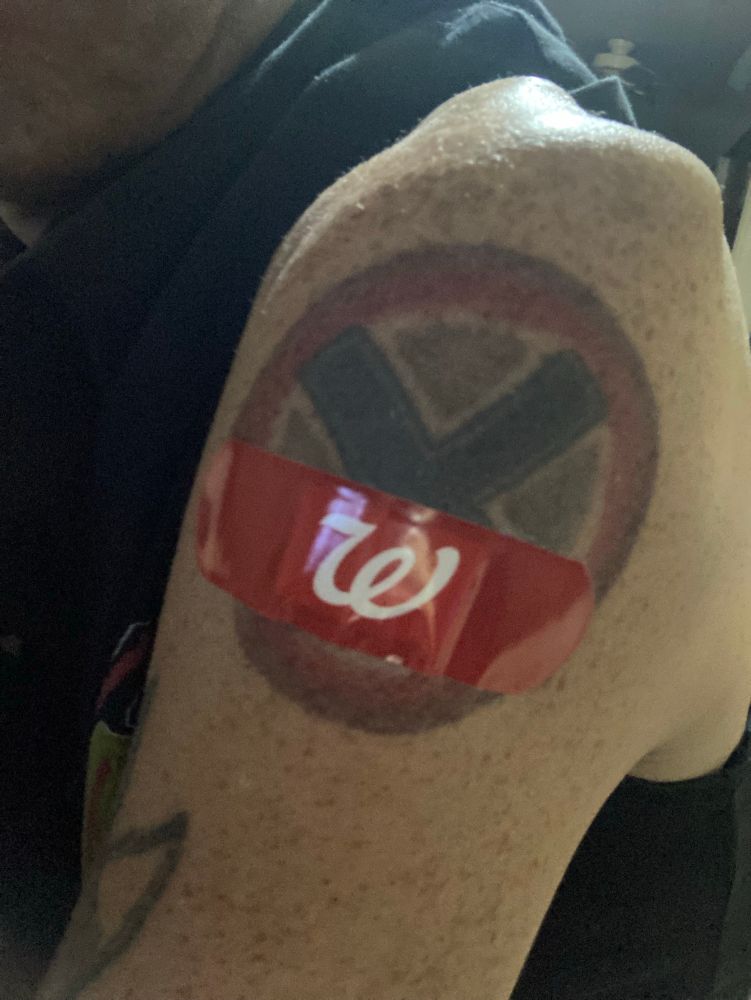 A red Walgreens bandaid rests comfortably against a vaccinated arm sporting an X-Men tattoo