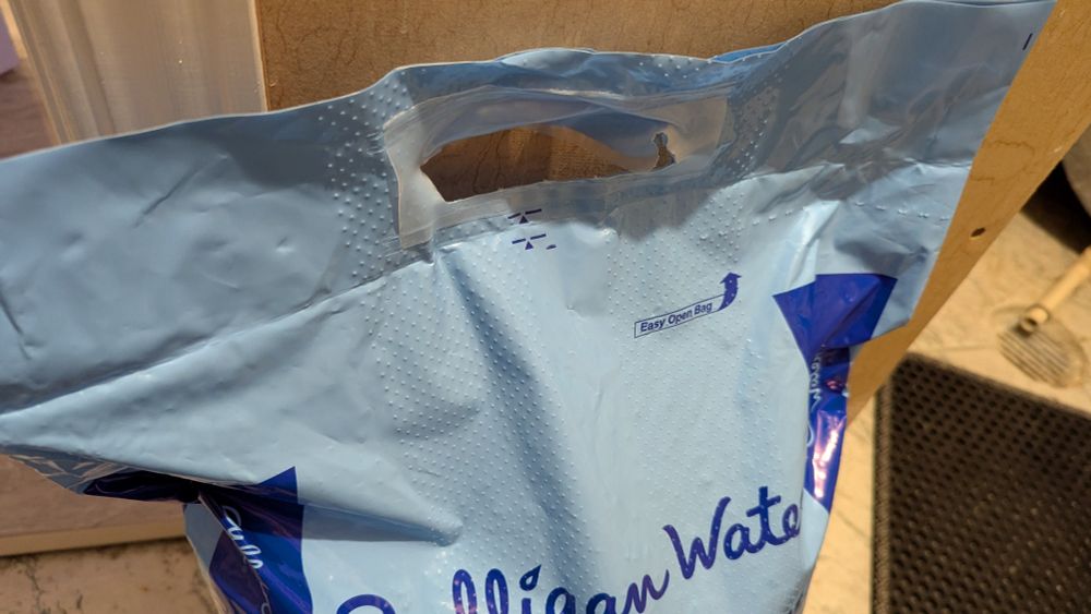 Bag of softener salt with "easy open bag" label in the top right corner pointing at a barely visible perforated strip.