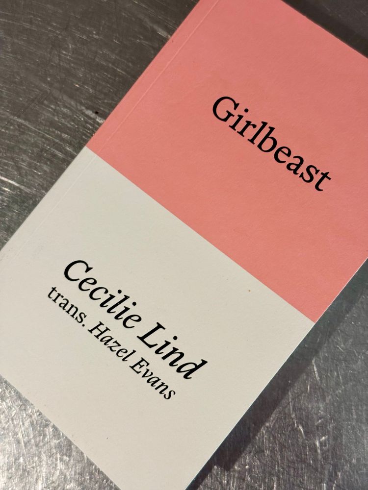 The book “Girlbeast” by Cecilie Lind, translated from Danish by Hazel Evans. The cover is half pink and half white with black text. 
