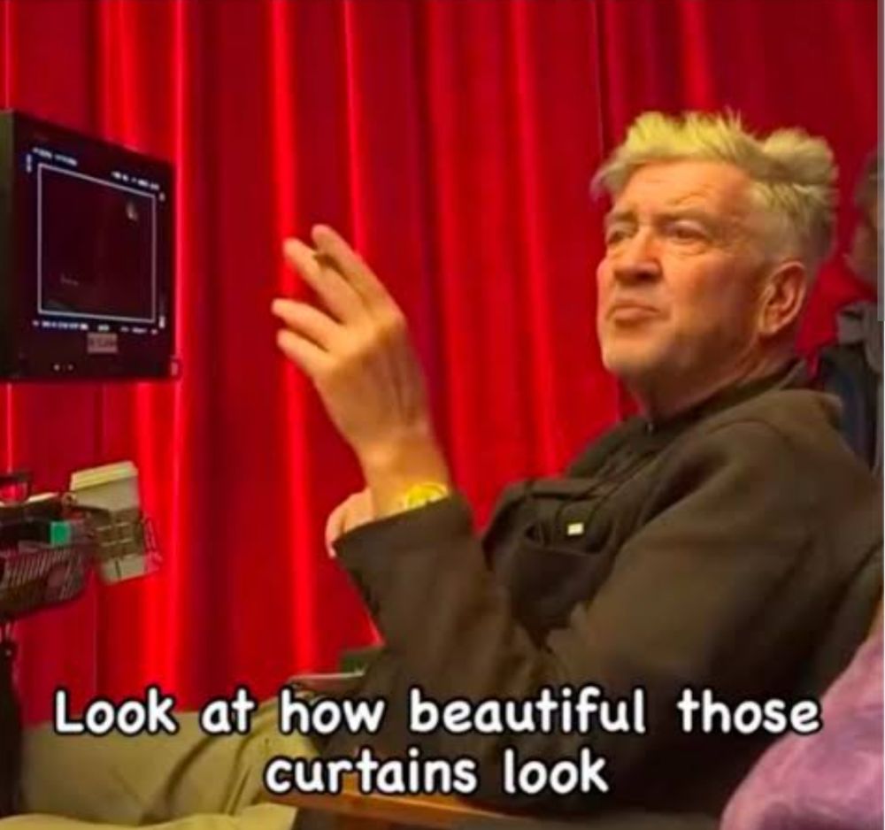 David Lynch in front of red curtains saying, " Look at how beautiful those curtains look."