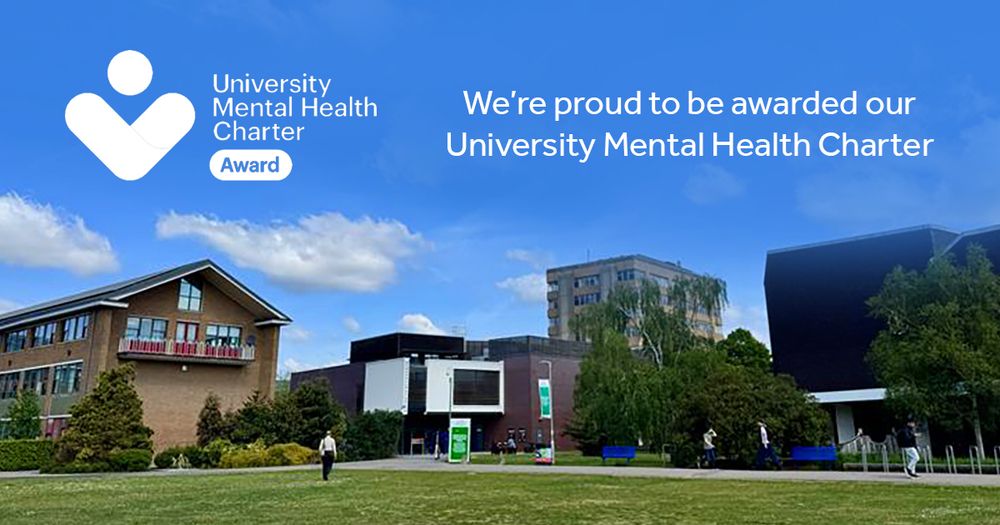A view across one of the lawns in the University of Reading's Quad on a sunny day with bright blue skies. The image includes an overlay of the University Mental Health Charter Award logo and text reading: We're proud to be awarded our University Mental Health Charter. 