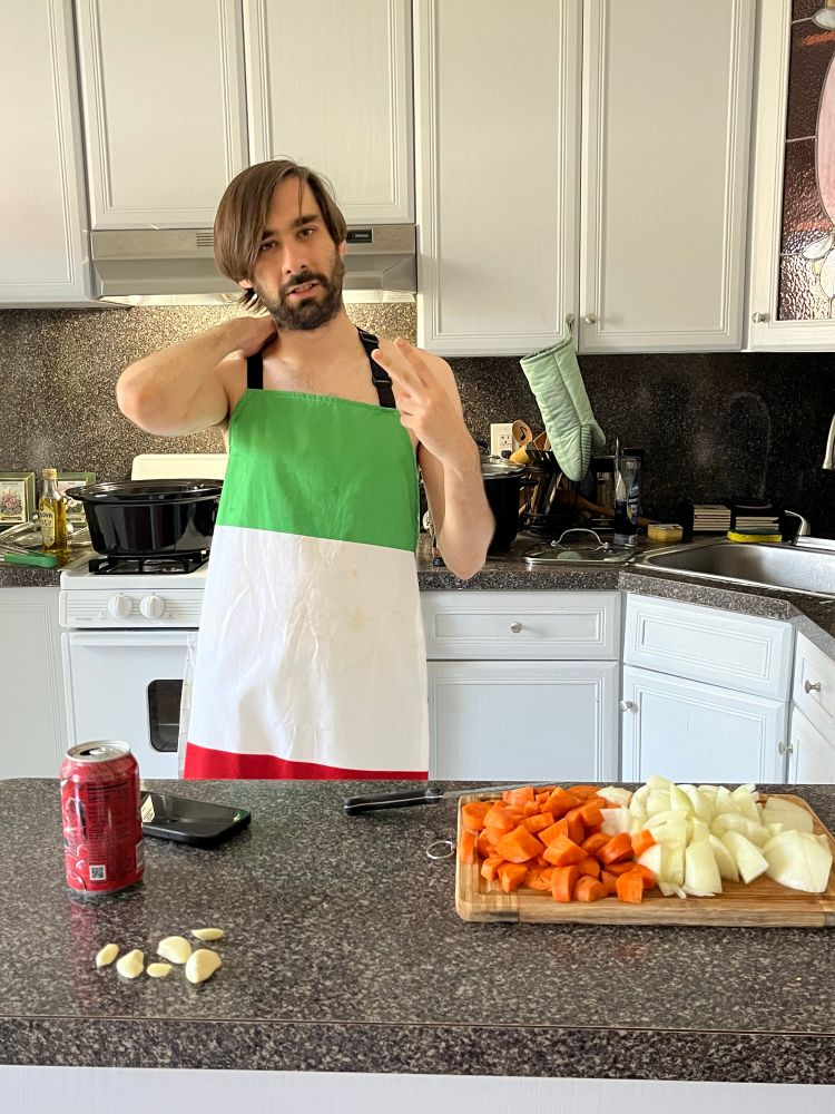 a man wearing only an italian flag apron stands in front of a tray of diced vegetables and yes, there is a code red on the counter 
