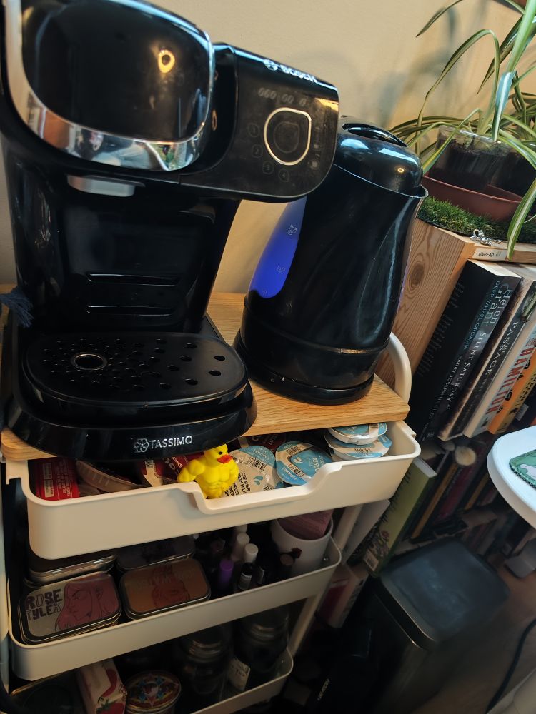 A Tassimo coffee machine next to a THICC black electric kettle with blue heating lights
