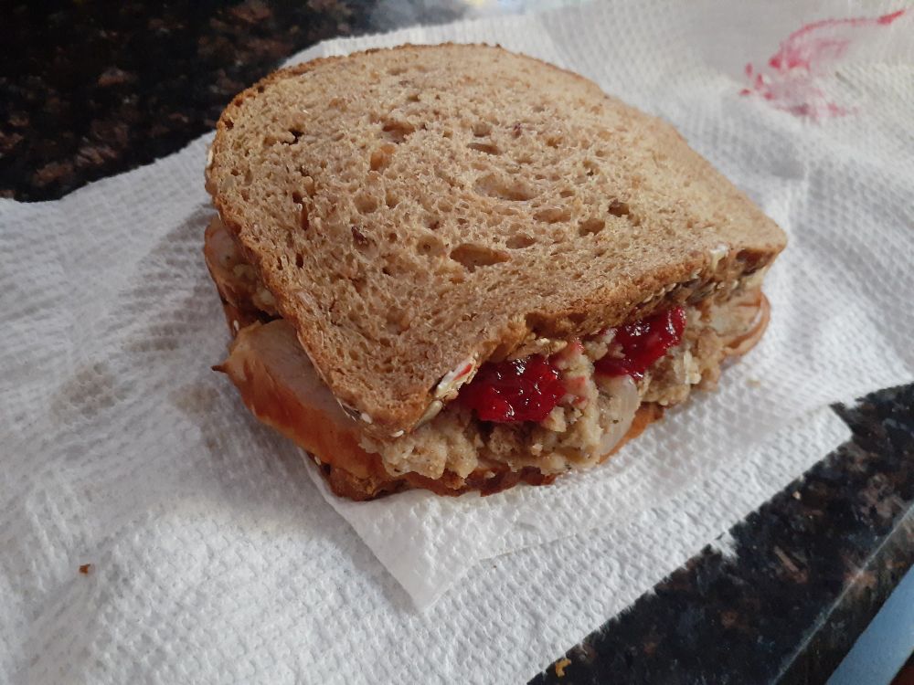 picture of a sandwich with turkey, stuffing, and cranberry sauce on a paper towel
