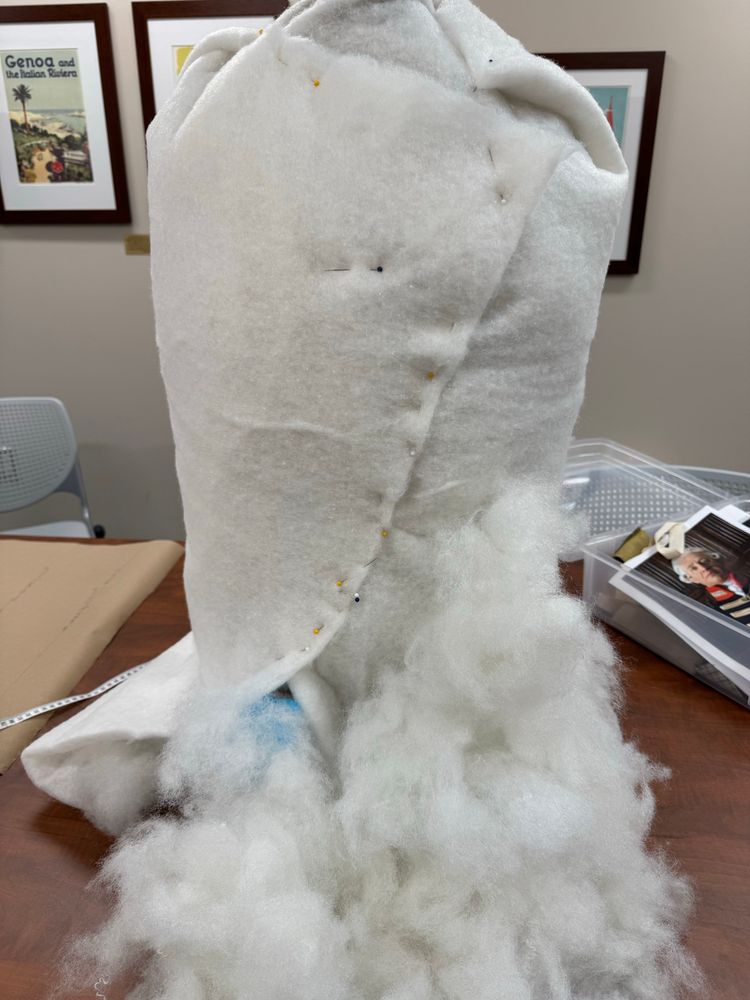 Form of a torso dressmakers dummy  with lots of stuffing piled in front of it 