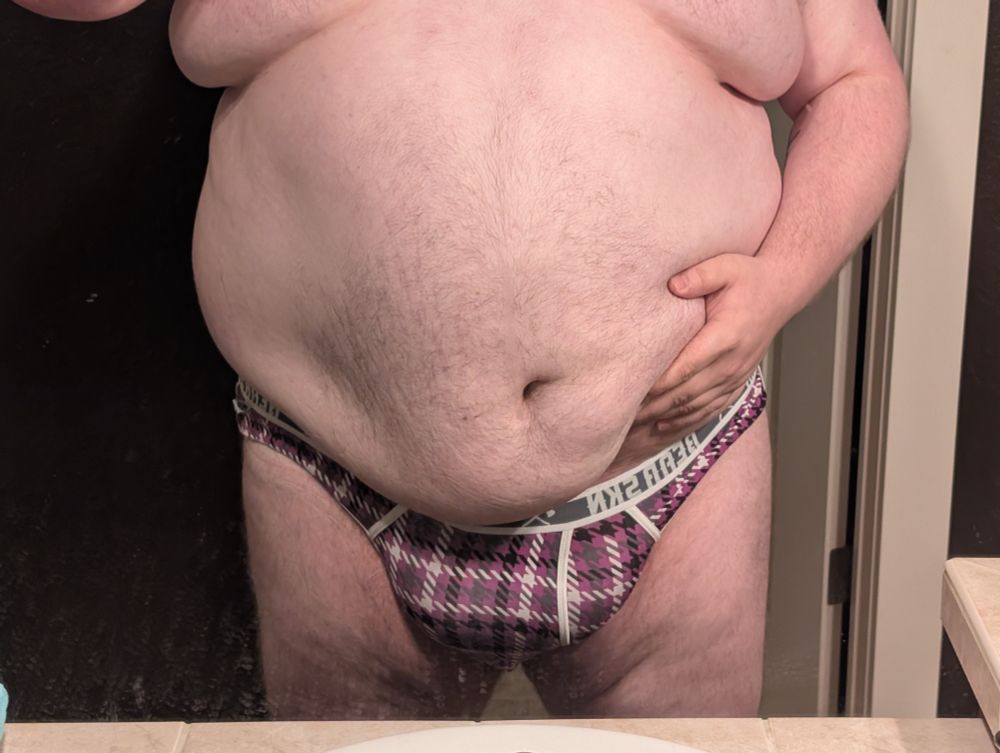 Tano in a jock, one hand lifting belly