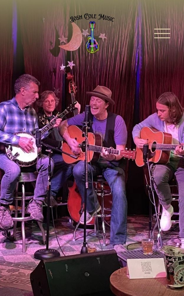 Photo of a bluegrass band on a stage with the Josh Cole Band logo on top. 4 men playing instrument (a banjo, 2 guitars, and a stand up bass).