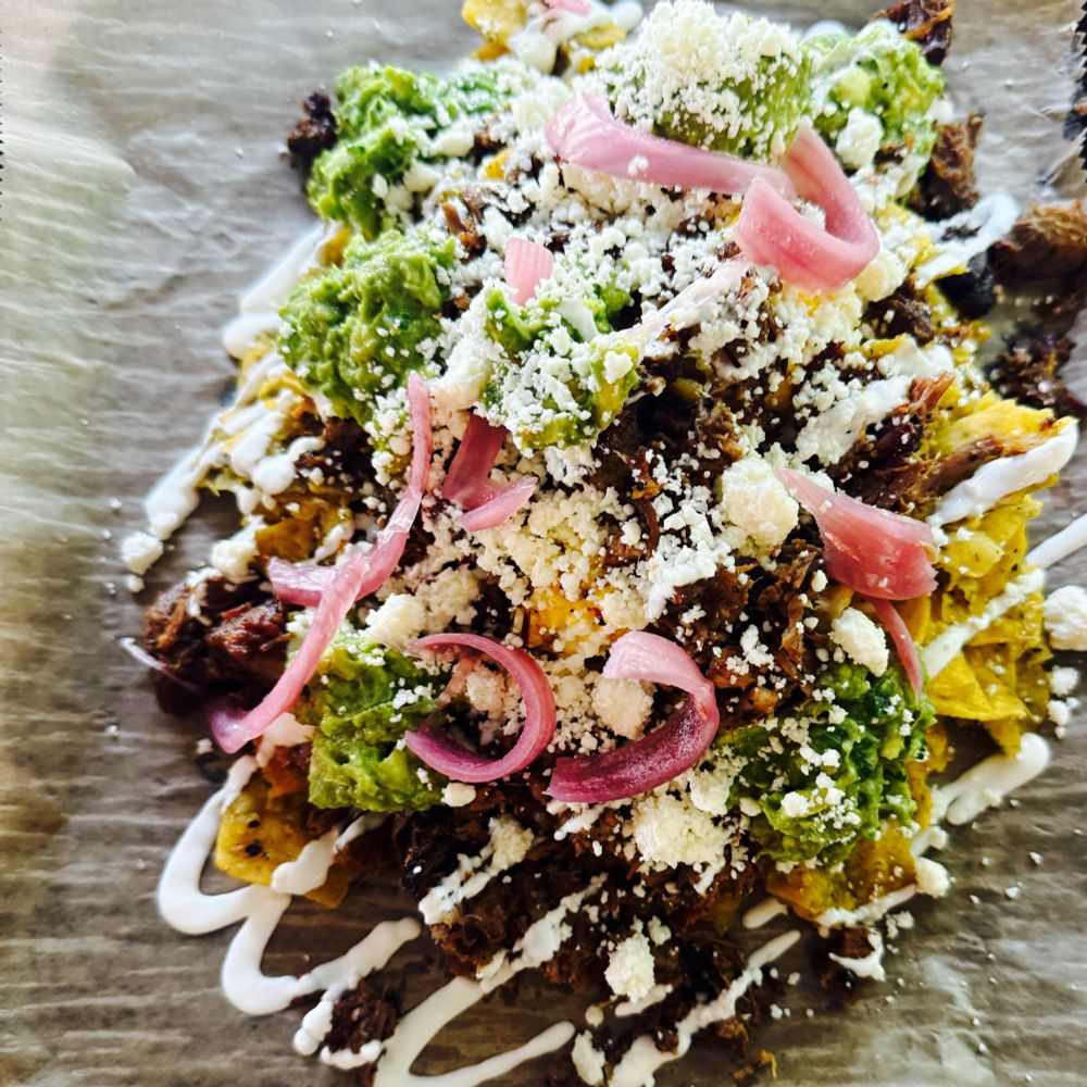 Chilaquiles with brisket, guacamole, queso fresco, sour cream, scrambled eggs, beans, and pickled red onions