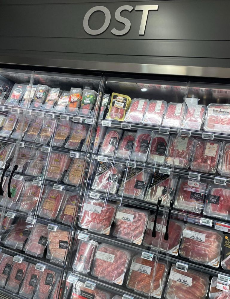 En skylt med texten OST ovanför kyldisk full av charkvaror.